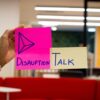 Image of a hand with two sticky notes, one in pink writing "disruption" and another in yellow writing "TALK".