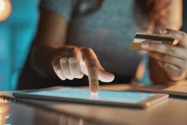 Cropped shot of an unrecognizable businesswoman using her tablet to make payments while working late in the office