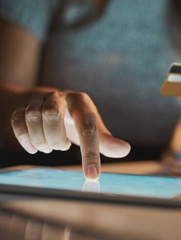 Cropped shot of an unrecognizable businesswoman using her tablet to make payments while working late in the office