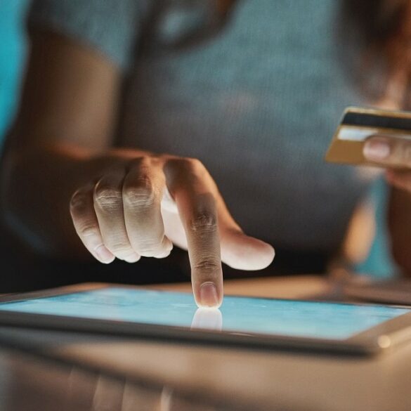 Cropped shot of an unrecognizable businesswoman using her tablet to make payments while working late in the office