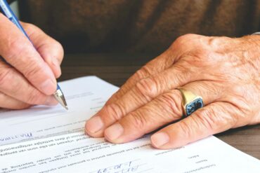 Photo of an elderly person signing a contract