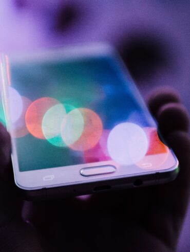Photo of a person holding a smartphone with a purple futuristic background and overlay effect