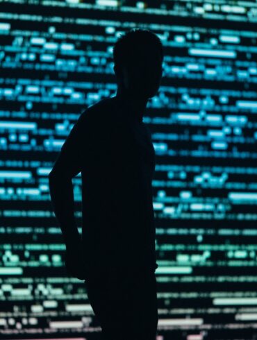 Photo of a man in a darkened-shadow style with compuristic blue and green patterns in the background