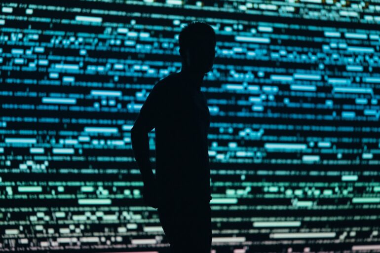 Photo of a man in a darkened-shadow style with compuristic blue and green patterns in the background