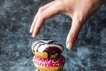 Photo of a hand reaching out to take a donut, depicting instant gratification
