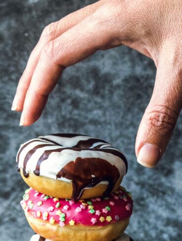 Photo of a hand reaching out to take a donut, depicting instant gratification