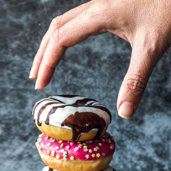Photo of a hand reaching out to take a donut, depicting instant gratification