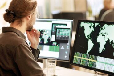 Photo of a man looking at a computer screen with a map of the world, representing a multinational outlook.