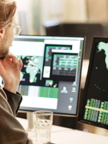 Photo of a man looking at a computer screen with a map of the world, representing a multinational outlook.