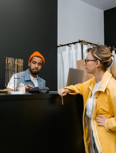 Photo of a woman in a shop making a payment at the counter using her credit card