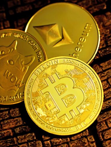 Photo of three physical coins with popular cryptocurrency symbols