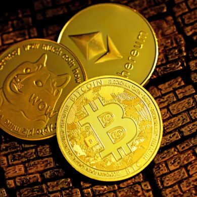 Photo of three physical coins with popular cryptocurrency symbols