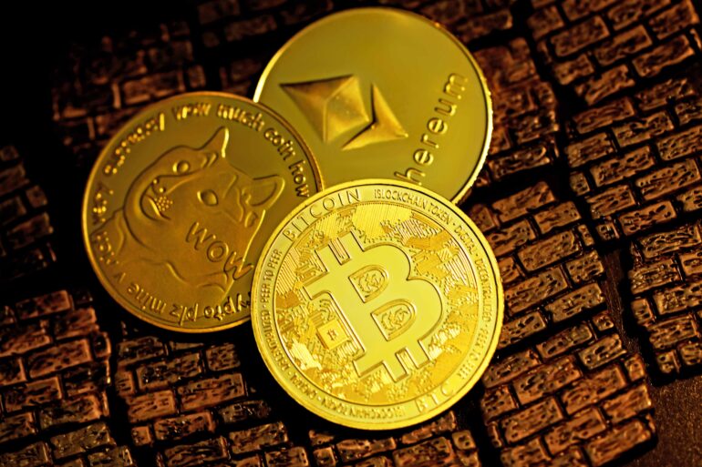 Photo of three physical coins with popular cryptocurrency symbols