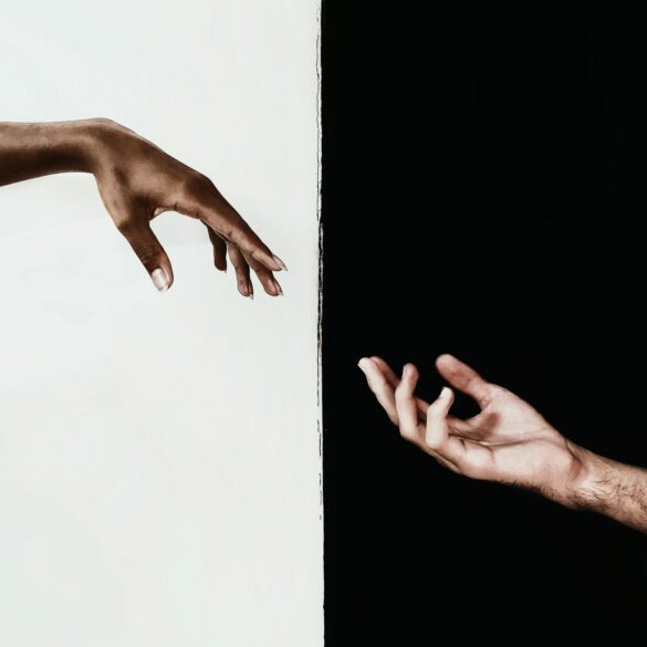 An interesting photo of an artistic style image with a white persons hand pointing towards a black persons hand.