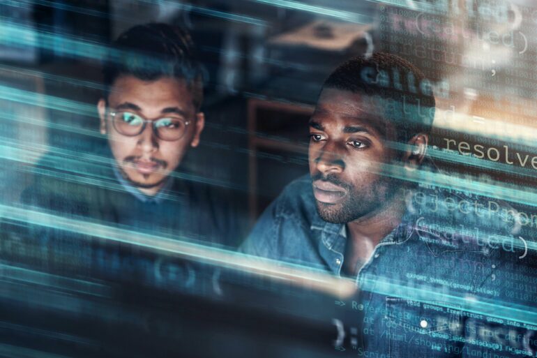 Photo of two men coding on a computer screen with an overlay over the image showing codes