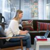 Photo of a woman using a laptop on her coffee table to make a conference call while working from home