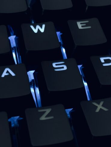 A close-up photo of a backlit qwerty keyboard in the dark