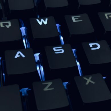 A close-up photo of a backlit qwerty keyboard in the dark