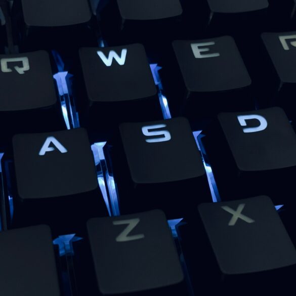 A close-up photo of a backlit qwerty keyboard in the dark