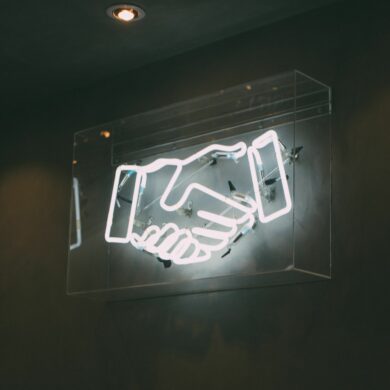 Photo of hand-shake neon lights flashing on the wall at night