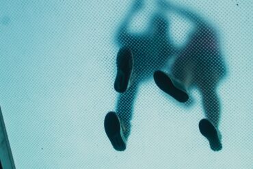 Two blurred people's footsteps from underneath a see-through walkpath.