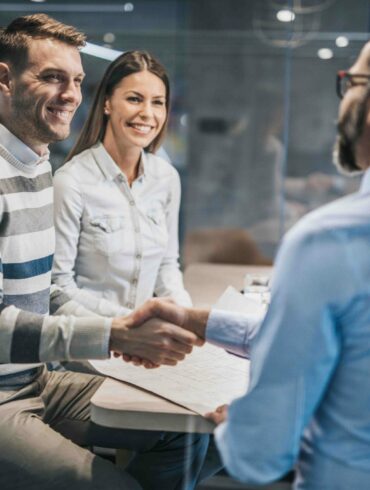 Photo of a couple in a corporate office, with the two men shaking hands.