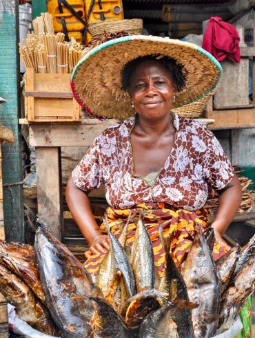 Woman of an African fish sales woman wearing a hat and smiling