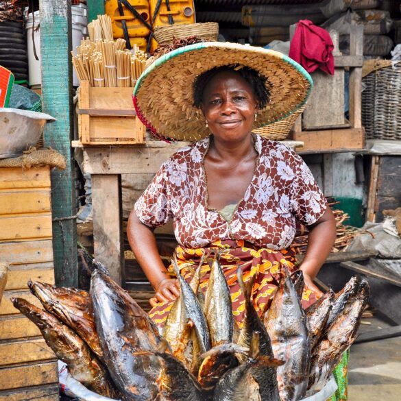 Woman of an African fish sales woman wearing a hat and smiling