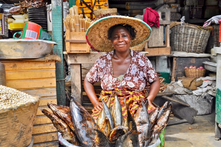 Woman of an African fish sales woman wearing a hat and smiling