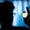 Photo of a shadowed man holding a Bitcoin coin